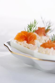 Appetizer of stuffed eggs stuffed with salmon pate and yolks with salmon slices. Holiday table idea

