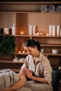 A cosmetologist girl does a facial and neck massage to a girl in the office for skin elasticity.