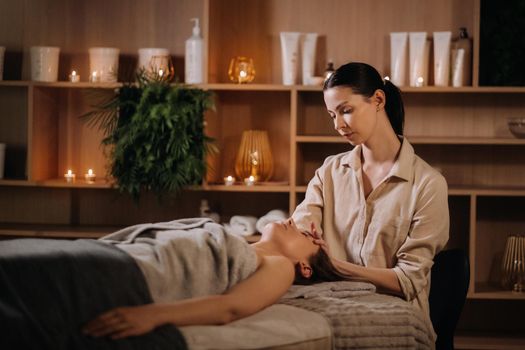 A cosmetologist girl does a facial and neck massage to a girl in the office for skin elasticity.