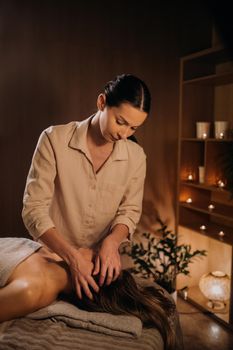 A masseuse gives a head massage to a woman at the spa. A professional masseur massages the head of a girl lying in a spa center.