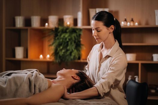 A cosmetologist girl does a facial and neck massage to a girl in the office for skin elasticity.