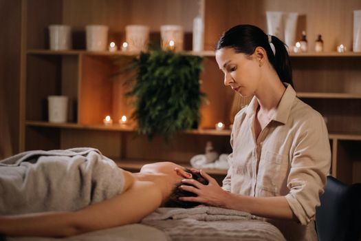 A cosmetologist girl does a facial and neck massage to a girl in the office for skin elasticity.