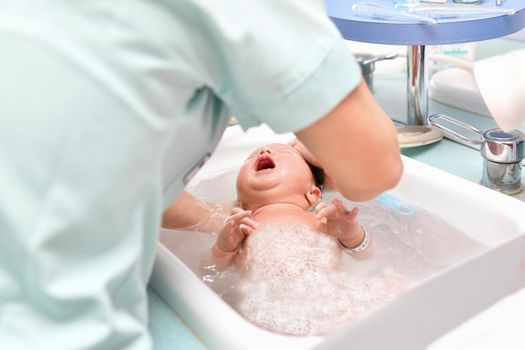 A nurse gives the first bath of a newborn baby