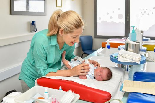 Mother cares for her newborn baby in the maternity hospital. First bath.
