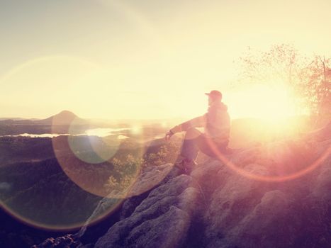 Man stands alone on the peak of rock. Hiker watching to autumn Sun at horizon . Beautiful moment