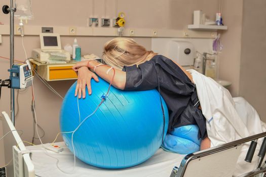 Woman during contractions on a blue fitness ball Parturition hospital