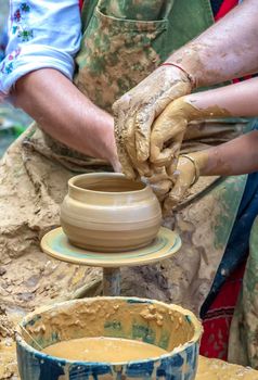 A master of pottery craftsmanship teaches a child who wants to learn how to sculpt a jug. Pottery master class.