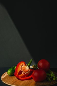 branches of fresh green asparagus, peppers, tomatoes and cucumbers on a wooden board, dark gray background, top view. Basic trend concept with copy space