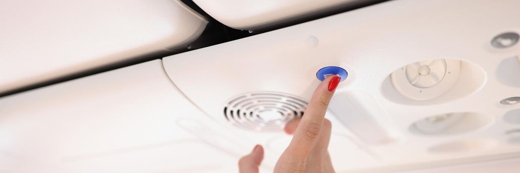 Close-up of airplane passenger female press blue button on plane with finger, stewardess call panel. Flight attendant call knob. Aircraft, service concept