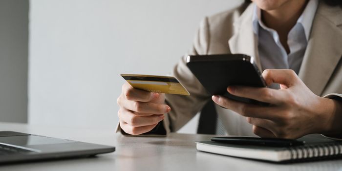 Close up female hands holding credit card and smartphone, young woman paying online, using banking service, entering information, shopping, ordering in internet store, doing secure payment.