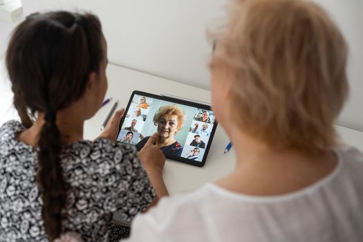 Cute little girl with her grandmother looking at tablet at home.