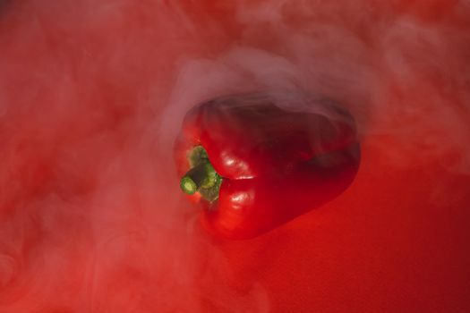 SWEET, fresh RED PEPPER ON A RED BACKGROUND WITH A LIGHT SMOKE.