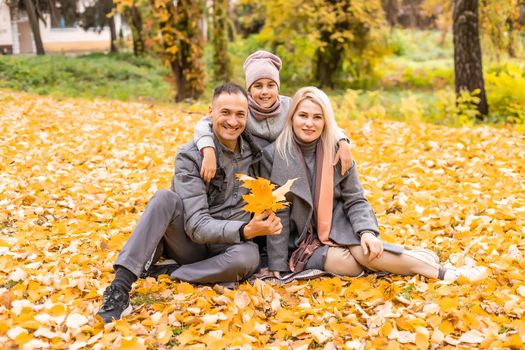 A Family of four enjoying golden leaves in autumn park.