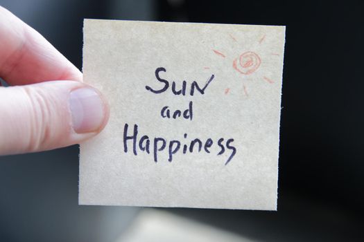 Sun and happiness. Creative concept. Hand holding a tag with the inscription. High quality photo