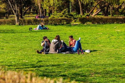 Targoviste, Romania - 2019. Group of people on the grass in the central park.