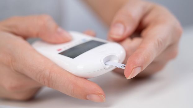 Woman measures blood sugar level with a glucometer