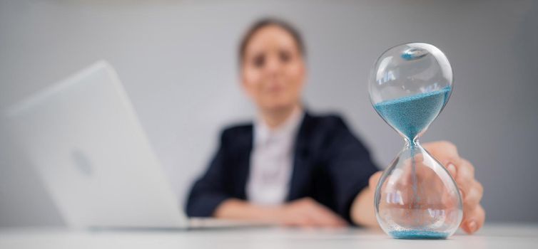 Business woman flipping an hourglass at her desk