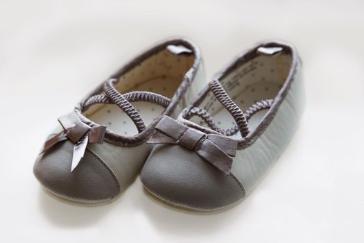 Cute baby shoes against a white background. Anticipating the arrival of a little girl and ready to play dress up with grey ballerina pumps with a cute bow. Newborn booties for pregnancy announcement.