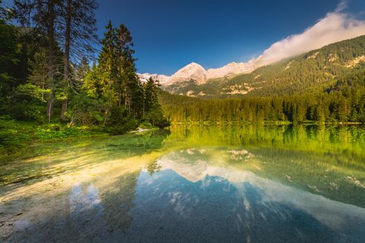 Idyllic Lake Tovel reflection at peaceful sunrise, Dolomites alps, Italy.