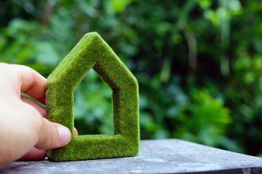 hand holding eco house icon in nature