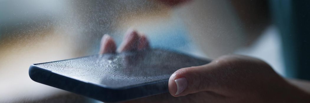 Close-up of spray antiseptic on mobile phone screen, antibacterial and disinfecting liquid. Protective glass on phone screen. Clean, prevent virus concept