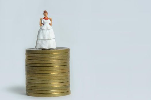 Wedding dress budget for bride, miniature people illustration concept. Woman standing above coin money stack. Image photo