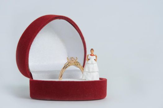 Women miniature people fitting wedding dress standing above ring box, isolated white background. Image photo