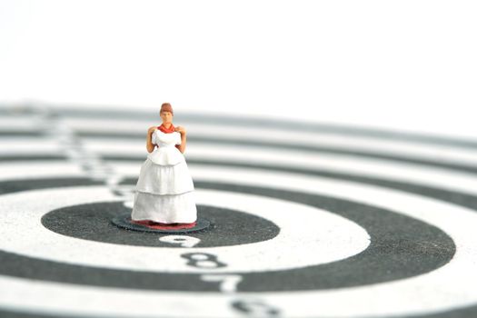Wedding married target goal conceptual miniature people toy photography. Women trying wedding dress standing on dartboard. Image photo
