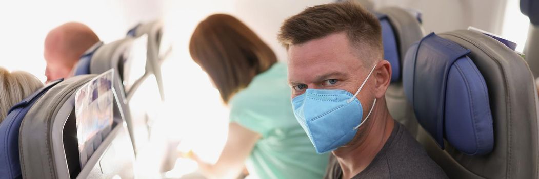 Portrait of couple flying on airplane, reading magazine to kill time. Fly high in sky, wear face masks on flight. Airplane, coronavirus, pandemic concept