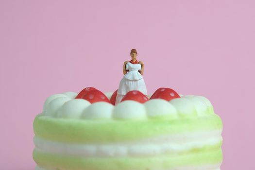 Woman dieting from cake before wedding day concept. Miniature people toys photography, girl holding wedding dress. Image photo