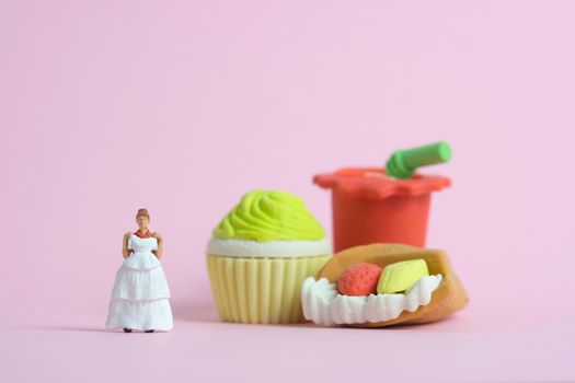 Woman dieting from junk food before wedding day concept. Miniature people toys photography, girl holding wedding dress. Image photo