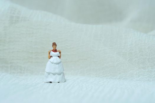 Women miniature people trying to choose wedding dress. Image photo