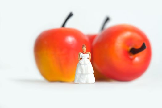 Diet plan before wedding or marriage day concept. Woman standing in front of apple with trying wedding dress. Miniature people, toys photography.