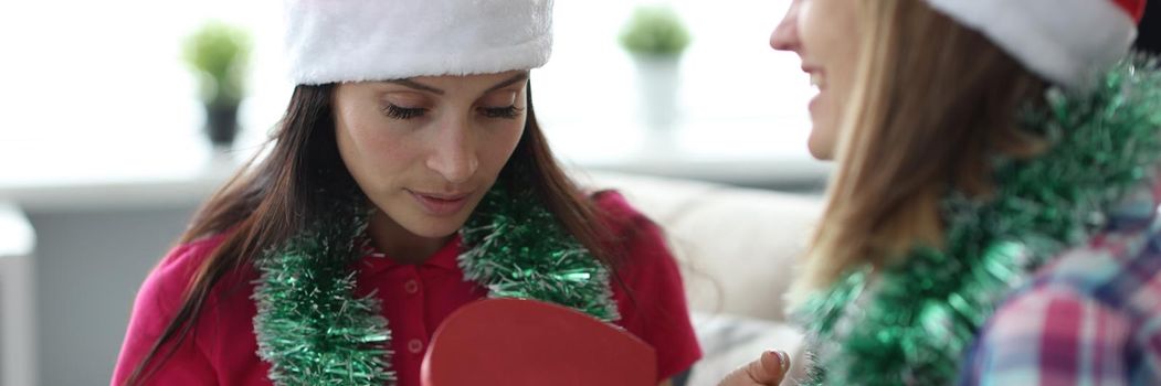 Portrait of female in santa claus hat open empty box, no present, practical joke. Female friends exchange gifts every year. Joke, prank, holiday concept