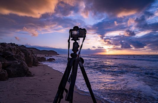 Camera on tripod - photographer work on sea beach