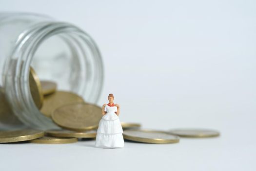 Wedding dress budget for bride, miniature people illustration concept. Woman standing above coin money jar. Image photo