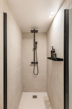 Modern shower zone with black rain head and hand held shower. Beige tiles in the bathroom