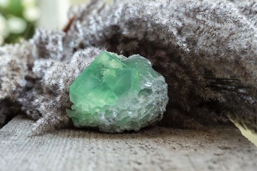 Green Fluorite Stone mineral gemstone close up on wooden background. Natural gem for collection or spiritual therapy.