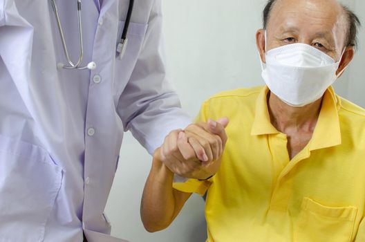 doctor is holding an elderly man's hand to cheer him up.