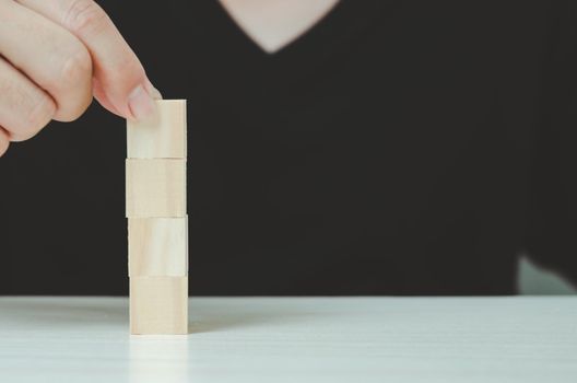 Hand putting and stacking blank wooden cubes  for icons or symbols.