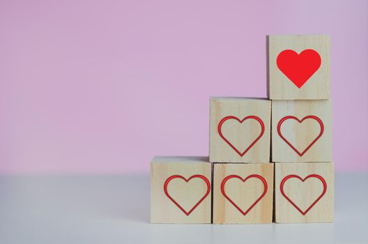 Wooden cubes with love  symbol heart red on the pink background and copy space.