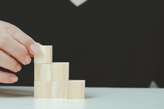 Hand putting and stacking blank wooden cubes  for icons or symbols.