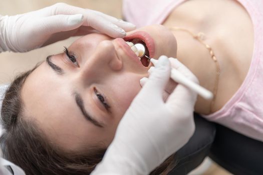 Dentist examining patient teeth with mirror in dentist clinic. Having dental checkup