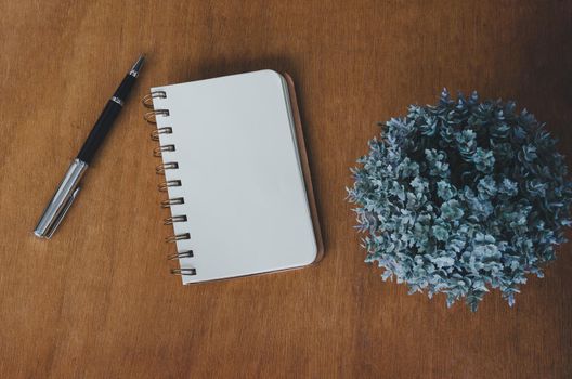 Notebook blank and pen and flower on vintage wood table background.Top view with copy space.