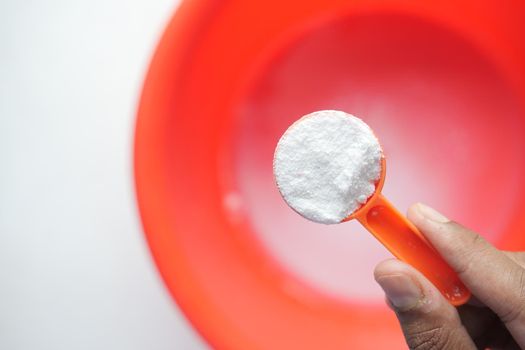 Washing powder in plastic spoon on blue background ,