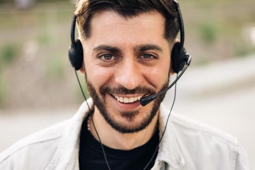 Close up of Face handsome man operator look at camera smile taking calls smile outdoor call center office business worker computer corporate headset job service group finance phone