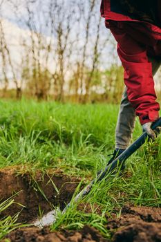 Farming, gardening, farming and people concept - unrecognizable young woman with a shovel digs the ground in a farm on a sunny day. High quality photo