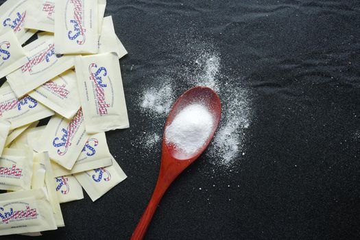 spoon of white sweetener on a black background