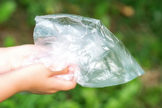Used empty plastic bag in hands of a little girl while cleaning the park from debris