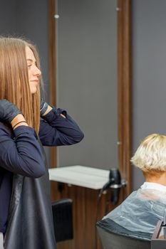 Female hairdresser puts on black apron before cutting the client's hair